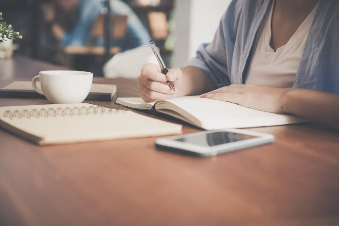 Person writing in a notebook at a café table
